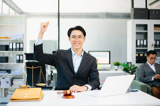 istock Confident Asian lawyer using tablet with gavel and justice scales on desk, looking at camera. Perfect for law, justice, business, and modern legal technology themes. 2240684201