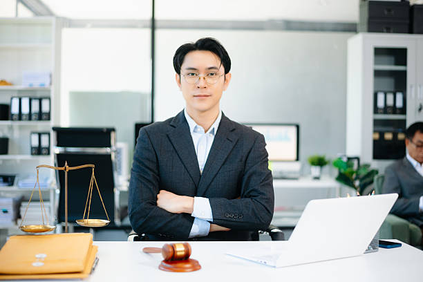 istock Confident Asian lawyer using tablet with gavel and justice scales on desk, looking at camera. Perfect for law, justice, business, and modern legal technology themes. 2240684213