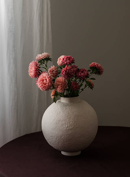 istock Bouquet of asters in a ceramic vase on a round table with a brown tablecloth 2240685955
