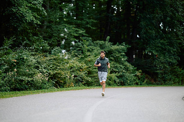 istock Man jogging on road in green forest 2240688227