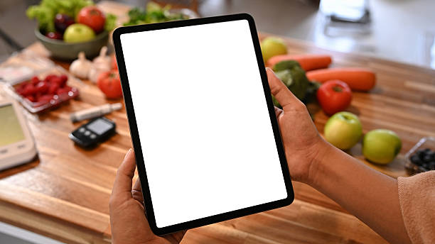 istock Person holding digital tablet with blank screen on kitchen counter surrounded by fresh fruits and vegetables for healthy lifestyle concept 2240689645