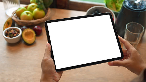 istock Person holding digital tablet with blank screen on kitchen counter surrounded by fresh fruits and vegetables for healthy lifestyle concept 2240689650