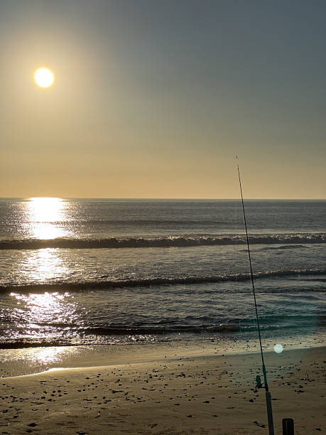 istock Fishing pole on the beach at sunset 2240693647
