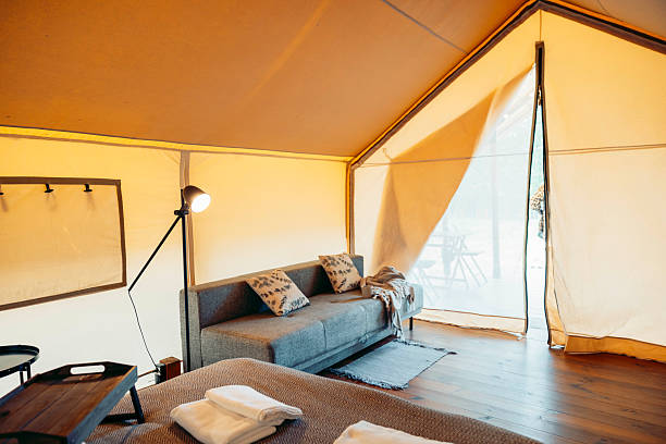 istock A cozy glamping tent interior with a comfortable sofa, wooden floor, and soft lighting. Large windows allow natural light to enter, creating a warm atmosphere. 2240694338