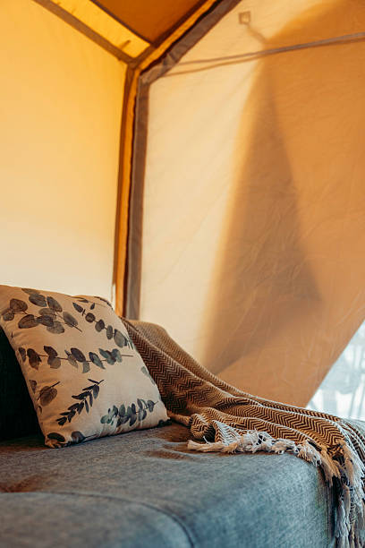 istock Cozy glamping tent interior with a comfortable sofa, decorative pillow, and a warm blanket. Soft lighting creates a relaxing atmosphere. 2240694408