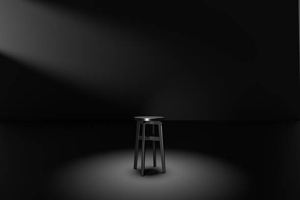 istock Lonely stool illuminated by a spotlight in a dark room 2240696365