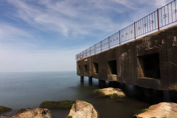 istock Old Pier and Rocks by the Calm Sea 2240698005