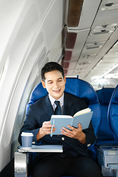 istock Young Asian executive excels in first class, multitasking with digital tablet, laptop and smartphone. Travel in style, work with grace. 2240699284