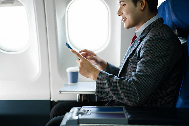 istock Confident businessman in first class holding coffee and using his smartphone, showcasing luxury air travel, success, and a modern professional lifestyle. 2240699308