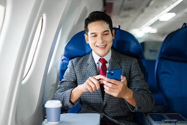 istock Confident businessman in first class holding coffee and using his smartphone, showcasing luxury air travel, success, and a modern professional lifestyle. 2240699309
