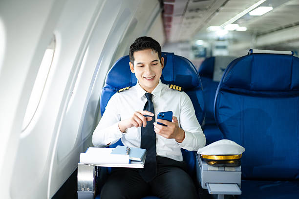 istock Confident pilot in uniform using smartphone in airplane cabin, ideal for aviation, communication, and travel lifestyle stock imagery. 2240699332