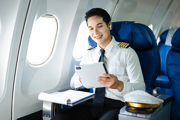 istock Confident pilot in uniform using smartphone in airplane cabin, ideal for aviation, communication, and travel lifestyle stock imagery. 2240699339
