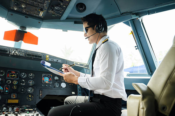 istock Professional airline pilot in uniform inspecting cockpit control panels during safety checks, ideal for aviation, travel, and airline safety themes. 2240699356