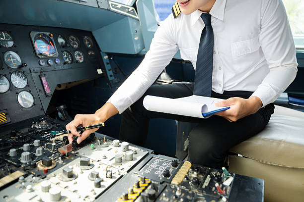 istock Professional airline pilot in uniform inspecting cockpit control panels during safety checks, ideal for aviation, travel, and airline safety themes. 2240699363