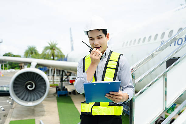istock Ground crew engineer in safety vest and helmet using walkie talkie while inspecting airplane, perfect for aviation, maintenance, and travel safety imagery 2240699395