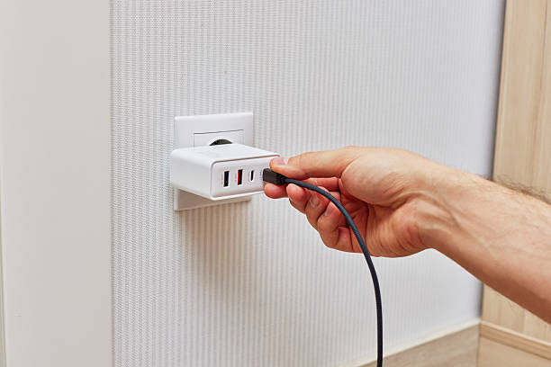 istock male hand insert a plug of the phone charger into socket. 2240701408