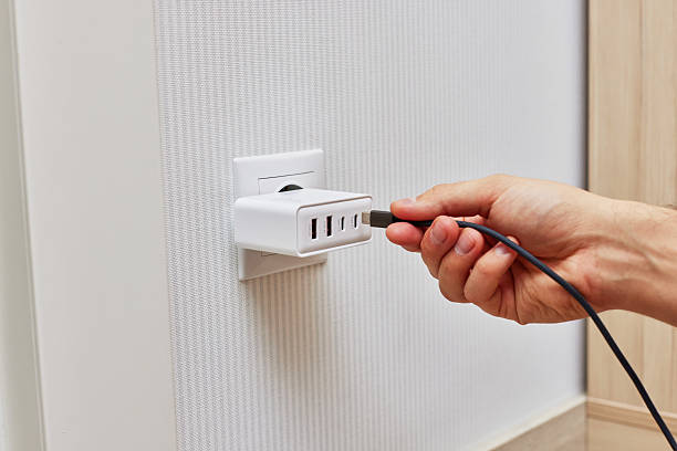 istock male hand insert a plug of the phone charger into socket. 2240701409