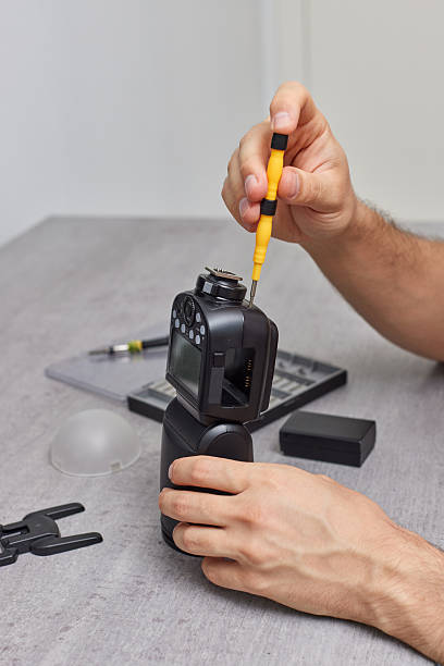 istock professional technician repairs camera flash. Photographic equipment service. 2240701476