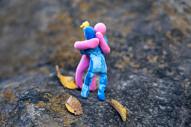 istock Romantic Plasticine Couple Hugging on Stone with Autumn Leaf 2240703323