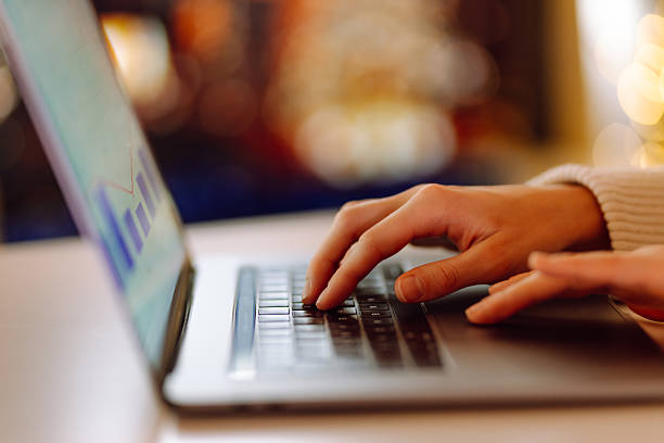 istock Close-up of hands typing on a laptop while sitting at a table in a cozy room. 2240703392