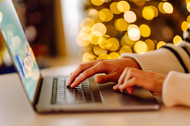 istock Close-up of hands typing on a laptop while sitting at a table in a cozy room. 2240703396