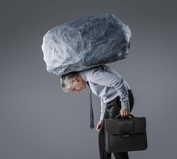 istock A Businessman Walking with a Huge Boulder on His Shoulders and a Briefcase in Hand 2240703570