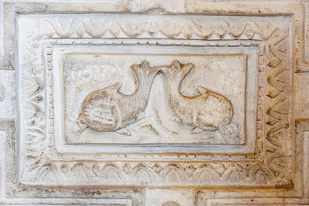 Ancient stone relief with two stylized fish in geometric frame. Fish as a symbol of Christianity before the fifth century