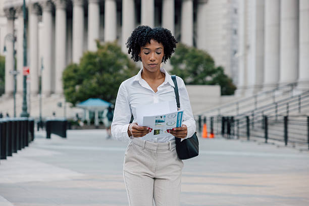 istock Professional woman reviewing documents while walking through city 2240705790