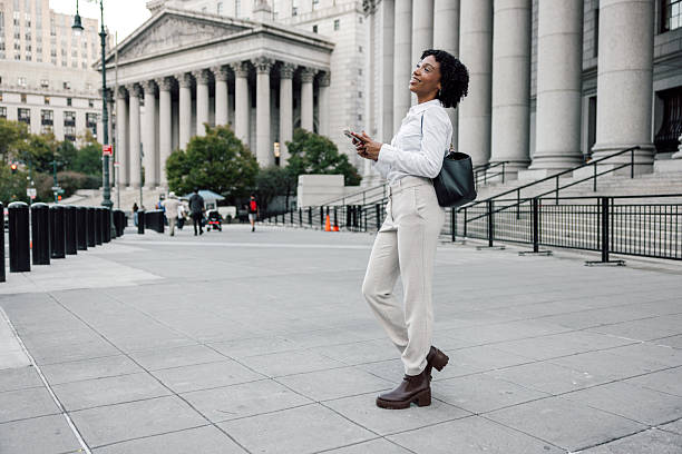 istock Elegant office worker walking in downtown area with mobile phone 2240706508