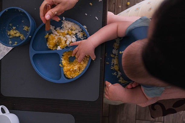 istock Baby Eating Rice and Eggs with Spoon 2240708554