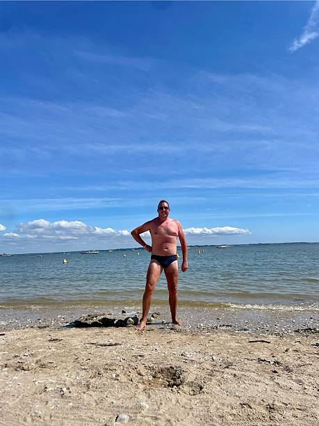 istock Man on a beach in swimming trunks 2240708642