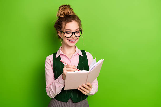istock Young female student writing in a notebook on a vibrant green background emphasizing education and learning 2240712874