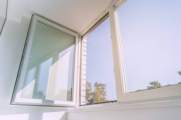 istock An open white plastic window in a bright, minimalist room, letting in sunlight and a summer breeze. The serene view from the apartment looks out on a clear blue sky and green trees. 2240715605