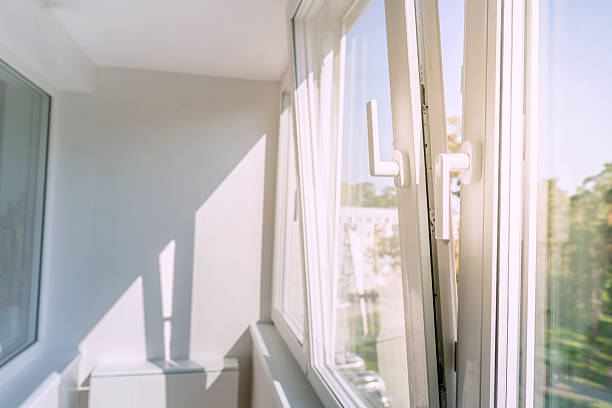 istock An open white plastic window in a bright, minimalist room, letting in sunlight and a breeze. The view from the apartment balcony looks out onto a peaceful green landscape. 2240715609