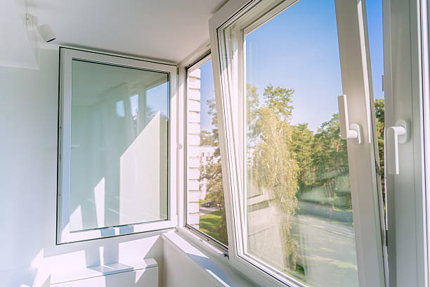 istock An open white plastic window in a bright, minimalist apartment balcony, letting in sunlight and a summer breeze. The peaceful view looks out on a clear blue sky and trees. 2240715610