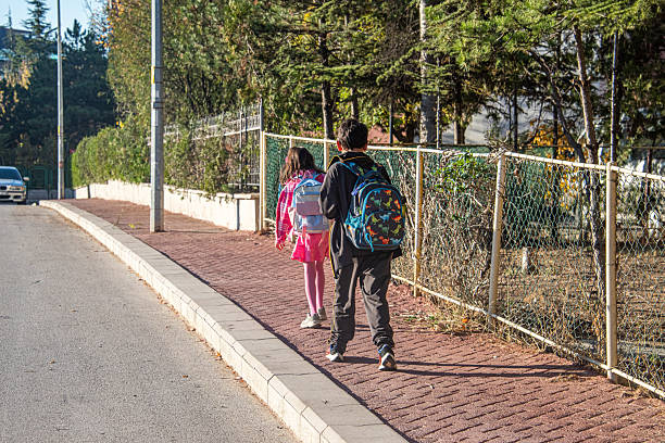 Sibling students walking to school on the sidewalk
