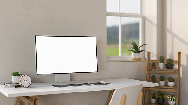 istock Blank screen computer aside clock and potted plant on white table aside wooden display shelf. 2240719526