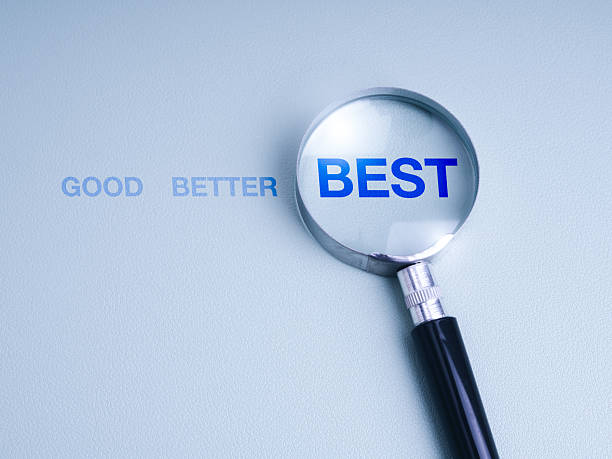Magnifying glass highlighting the word BEST from a sequence GOOD, BETTER, BEST on blue background, symbolizing excellence, improvement, strategic planning, work development, and decision making.