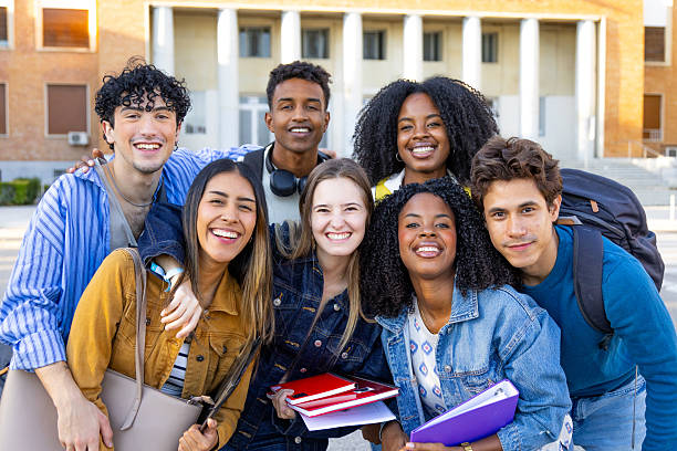 Happy diverse students posing together on university campus, embracing friendship and education, building community with their classmates