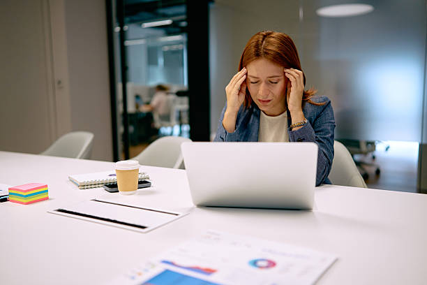 istock Stressed businesswoman working on laptop having headache in office 2240725061