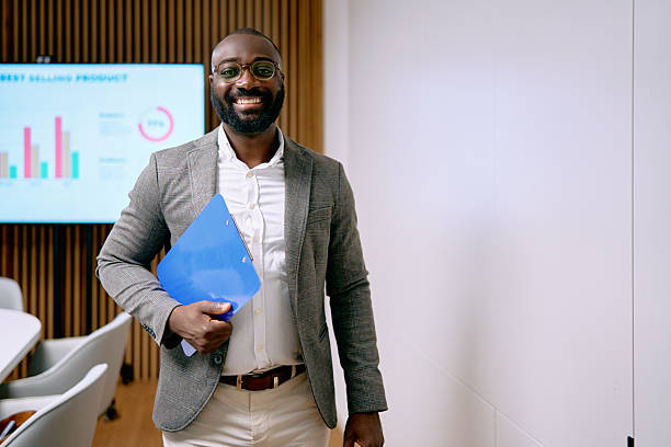 istock Smiling black businessman holding clipboard in modern office 2240725102