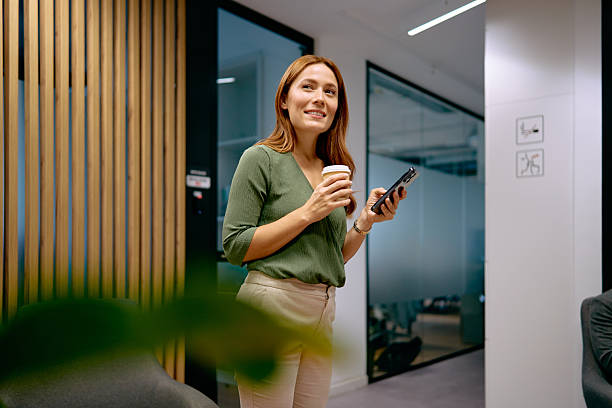 istock Businesswoman having coffee break checking smartphone in office 2240725337