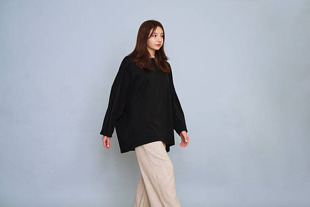 istock Confident woman strides forward in an oversized black shirt, epitomizing grace and modern fashion sensibilities. 2240727008