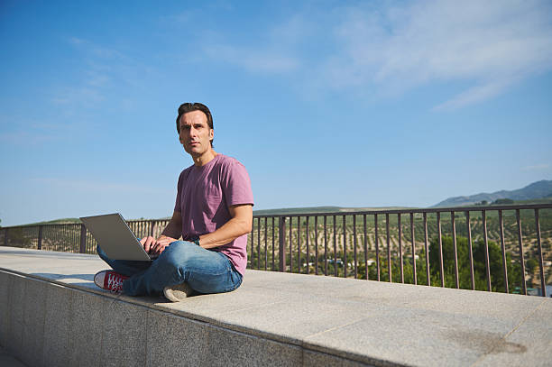 istock Focused Man Working on Laptop Outdoors on Scenic Hilltop 2240727727