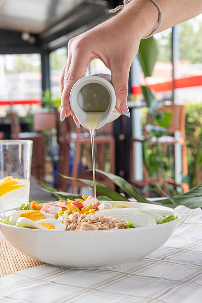 istock Hand pouring dressing on fresh tuna salad 2240728535