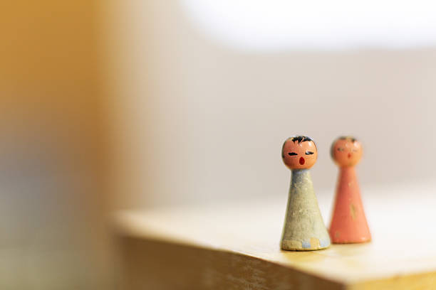 Two small wooden dolls. With light blue and pink clothes