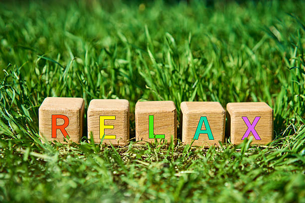 Wooden cube blocks with multicolor RELAX text on fresh green grass in sunlight