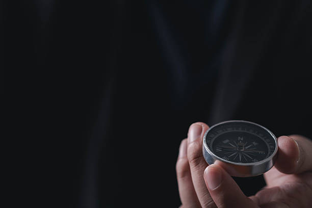 istock Close up of businessman holding a compass, symbolizing direction, leadership, decision making, vision, business strategy, guidance, and finding the right path to success. 2240738900