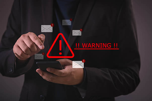 istock Businessman using smartphone with red warning alert and email icons, symbolizing phishing scam, cybersecurity threat, spam messages, online fraud, and digital security risks. 2240738911