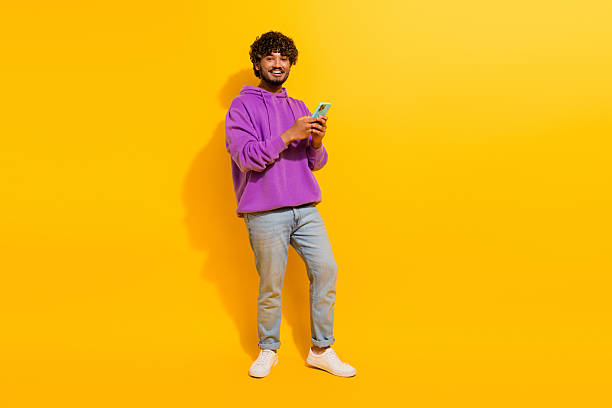istock Stylish young man with a phone in a vibrant setting expressing cheerful gestures and casual fashion for lifestyle 2240738964